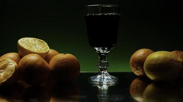 Rum drink being poured into long glass, isolated on colorful lighted wall background. Stock clip. Alcohol drink on the reflective table or bar counter with orange fruits. photo