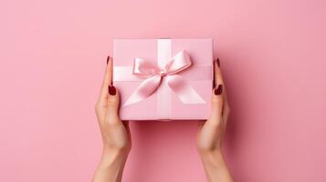 AI generated Female hands holding a pink gift box on a pink background, top view, woman's day, mother day photo