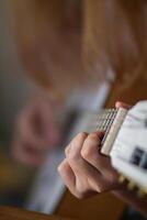 un joven mujer es practicando acústico guitarra a realizar en etapa en un música práctica habitación antes de ejecutando en orden a reducir errores. cerca arriba, un mujer mano participación guitarra acordes para práctica. foto