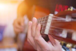 A young man is practicing playing guitar in a music practice room before performing in order to reduce the mistake of playing guitar on stage. Close Up Young man is holding guitar chords for practice. photo
