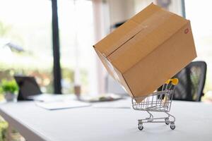 shopping cart lies on the table as symbol of online shopping and purchases. background mock up shopping cart is placed on table as the concept of online shopping during the long holiday season. photo