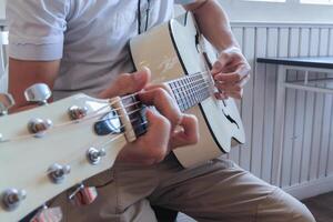 un joven hombre es practicando jugando guitarra en un música práctica habitación antes de ejecutando en orden a reducir el Error de jugando guitarra en escenario. cerca arriba joven hombre es participación guitarra acordes para práctica. foto