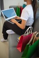 woman sitting in her room is happily shopping for gifts online with her credit card as she prepares for Christmas. woman uses laptop to access an online shopping website and pay with her credit card. photo