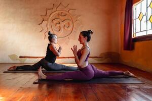 Two women of different ages practicing advanced yoga on a mat. photo