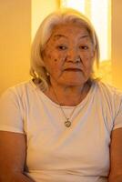 Portrait of older adult woman with gray hair looking at the camera with sad expression on her face. photo