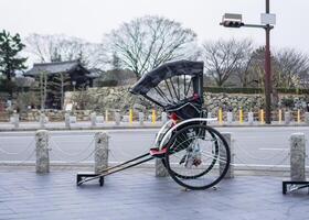 Ancient traditional japanese rickshaw parked on footpath photo