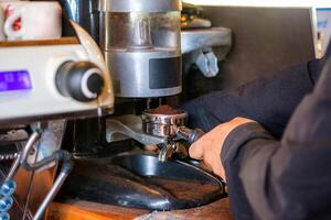 hombre barista haciendo café molienda polvo en café máquina foto