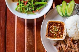 Grilled sliced pork with jasmine rice on wood table photo