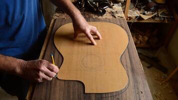 liutaio marcatura il forma di un' chitarra nel legna per produzione un' nuovo chitarra video