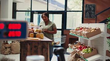 Retailer recommending types of paste for customer, showing her a variety of grains and pantry essentials. Vendor selling bulk items at local farmers market, low carbon footprint. Handheld shot. video