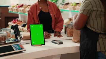 tablet tonen geïsoleerd groene scherm Scherm Bij contant geld register, rennen blanco Chroma sleutel sjabloon in lokaal boeren markt. verkoper hebben apparaatje met copyspace mockup lay-out in supermarkt. video