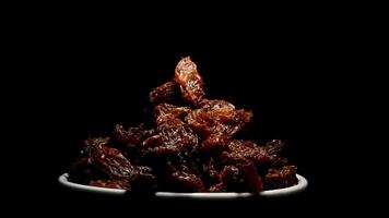 Raisins or dried grape in a bowl on black background gyrating video