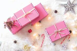 Pink gift boxes closed bow ribbon with bright lamp, candy and star on white carpet photo