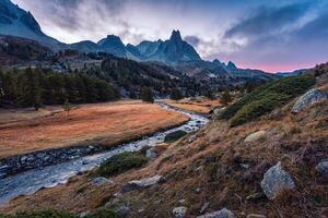 Sunset over Claree Valley with Main De Crepin peak and river flow through in larch forest during autumn at French Alps, France photo