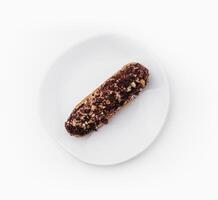 eclair with chocolate and nuts on a white plate photo