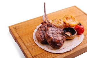 Grilled lamb chops on wooden board with herbs and spices photo