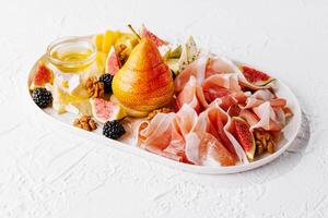 Italian antipasto with prosciutto, cheeses, nuts and fruits photo