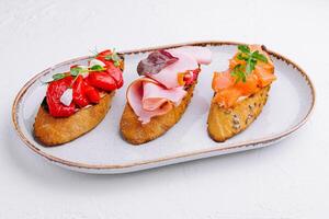 various bruschettas with ham, pepper and salmon photo