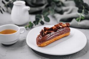 eclair con chocolate crema y avellanas y té foto