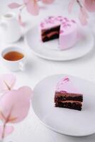 Piece of chocolate cake with pink cream photo