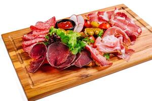 Variety of meats, sausages, salami, ham, olives, laid out on a wooden board photo