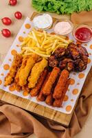 fried nuggets and spicy chicken legs, wings and french fries potatoes photo