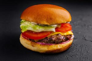 Appetizing cheeseburger on black stone closeup photo