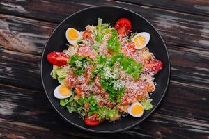 Salad with salmon, lettuce, boiled eggs, cherry tomatoes and parmesan cheese photo