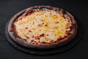 black pizza with cheese on stone photo