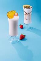 two glass cups of milkshake with dry pineapple and strawberries photo