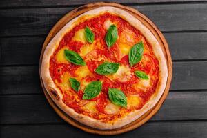 Pizza Margherita on black wood background photo