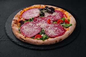 Delicious pizza with salami, arugula and tomatoes photo