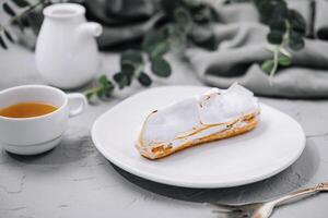 eclair with meringue and cup of tea photo