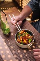 man eating with chopsticks gourmet fried squid Yakuza and drinks sesame and glass of juice photo