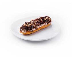 eclair with chocolate and nuts on a white plate photo