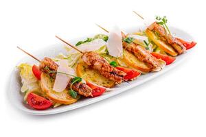 trendy Caesar salad with chicken on wooden skewers photo