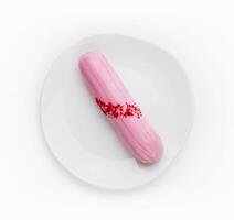 Eclair dessert with pink icing on plate photo