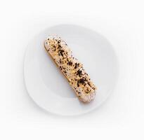 Eclair with cream and chocolate on plate photo