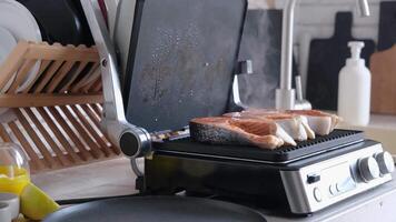 donna cucinando salmone bistecche su moderno elettrico griglia nel il cucina video