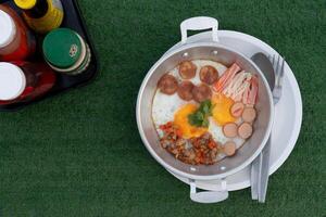 Above view of menu for simple breakfast menu. Pan-fried eggs served with condiments. Placed on artificial grass. photo