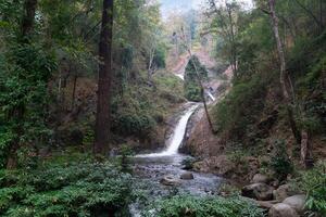 Chae Son waterfall flowing down a steep rocky hill. First level waterfall. Shallow pools and rocks, surrounded by lush green forests. At Chae Son National Park Thailand. photo