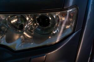 Close up on car headlights. The glass coating on the headlight surface is cloudy. Night light in the evening. photo