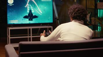 Gamer plays multiplayer game with spaceship shooting laser streams using crosshair overlay to hit targets. Ray tracing graphics and high FPS scifi videogame displayed on TV screen video