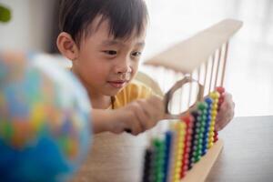 A young cute Asian boy is using the abacus with colored beads to learn how to count at home photo