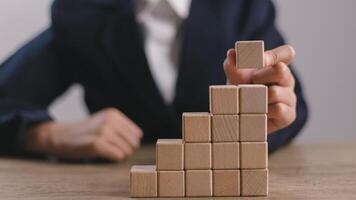 Businesswomen stack blank wooden cubes on the table with copy space, empty wooden cubes for input wording, and an infographic icon. photo