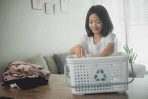 Recycle clothes concept. Asian little girl with a recycling box full of clothes. photo