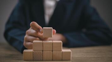 Businesswomen stack blank wooden cubes on the table with copy space, empty wooden cubes for input wording, and an infographic icon. photo