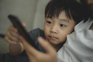 Child-addicted phone concepts. Asian boy playing smartphone, kid use telephone, watching smartphone. photo