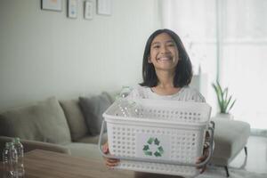 asiático pequeño muchachas separando reciclar el plastico botellas a basura compartimiento. foto