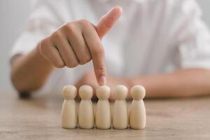 hora gerente humano recursos o del empleador mano elige a tomar persona de madera muñeca. el líder soportes fuera desde el multitud. mirando para bueno obrero. hora, hmm, hrd conceptos. foto